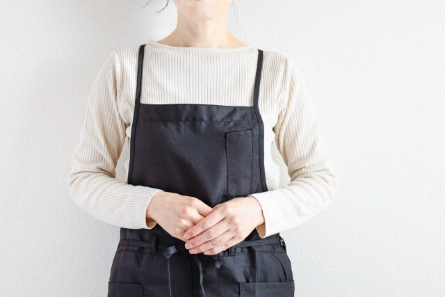 エプロンを着た女性スタッフが体の前で手を組む写真