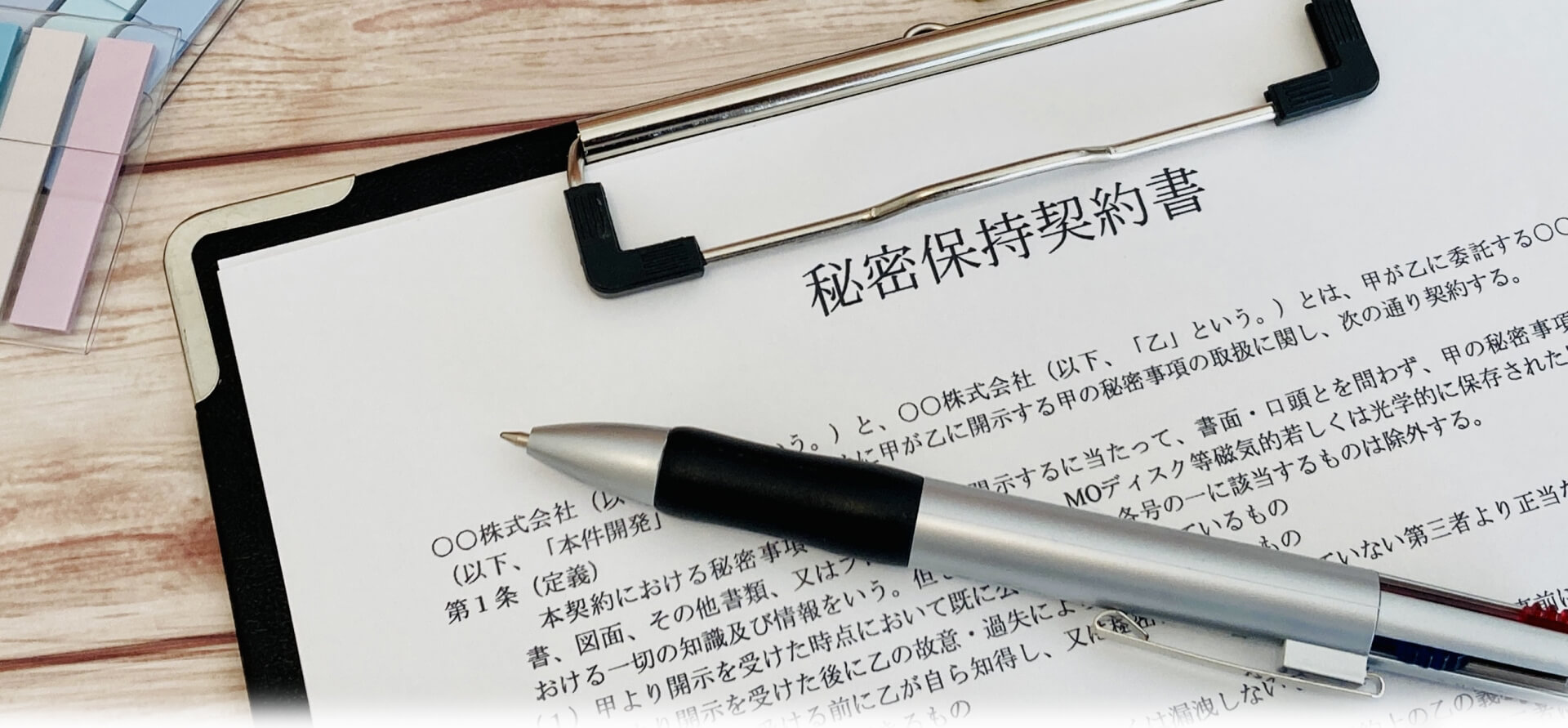 「秘密保持契約書」と書かれた紙とペンの写真